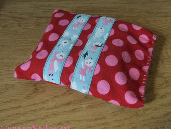 Small flex frame purse made from red and pink polka dot fabric with blue ribbons across.