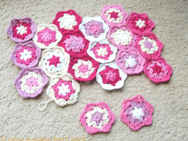 Overhead view of a pile of crocheted hexagons in white and pink colours.