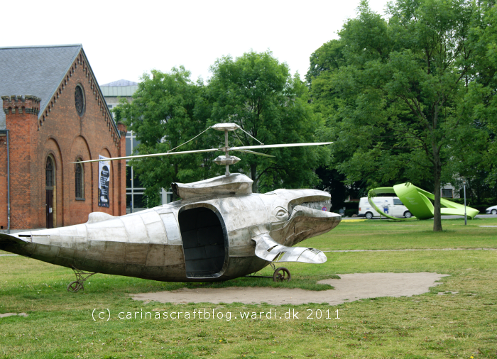 Humpback Gunship by Benjamin Gilbert. A large metal sculpture of a humpback whale with helicopter rotors on its back.