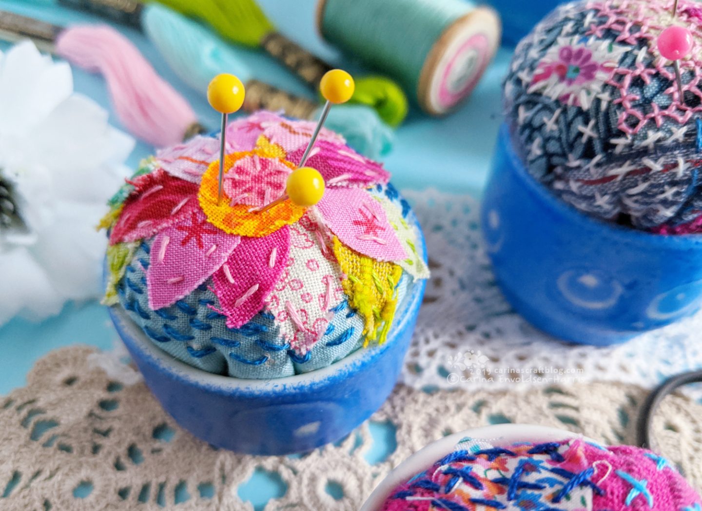 Egg cups turned into pincushions. Decorated with fabric scraps and stitching.