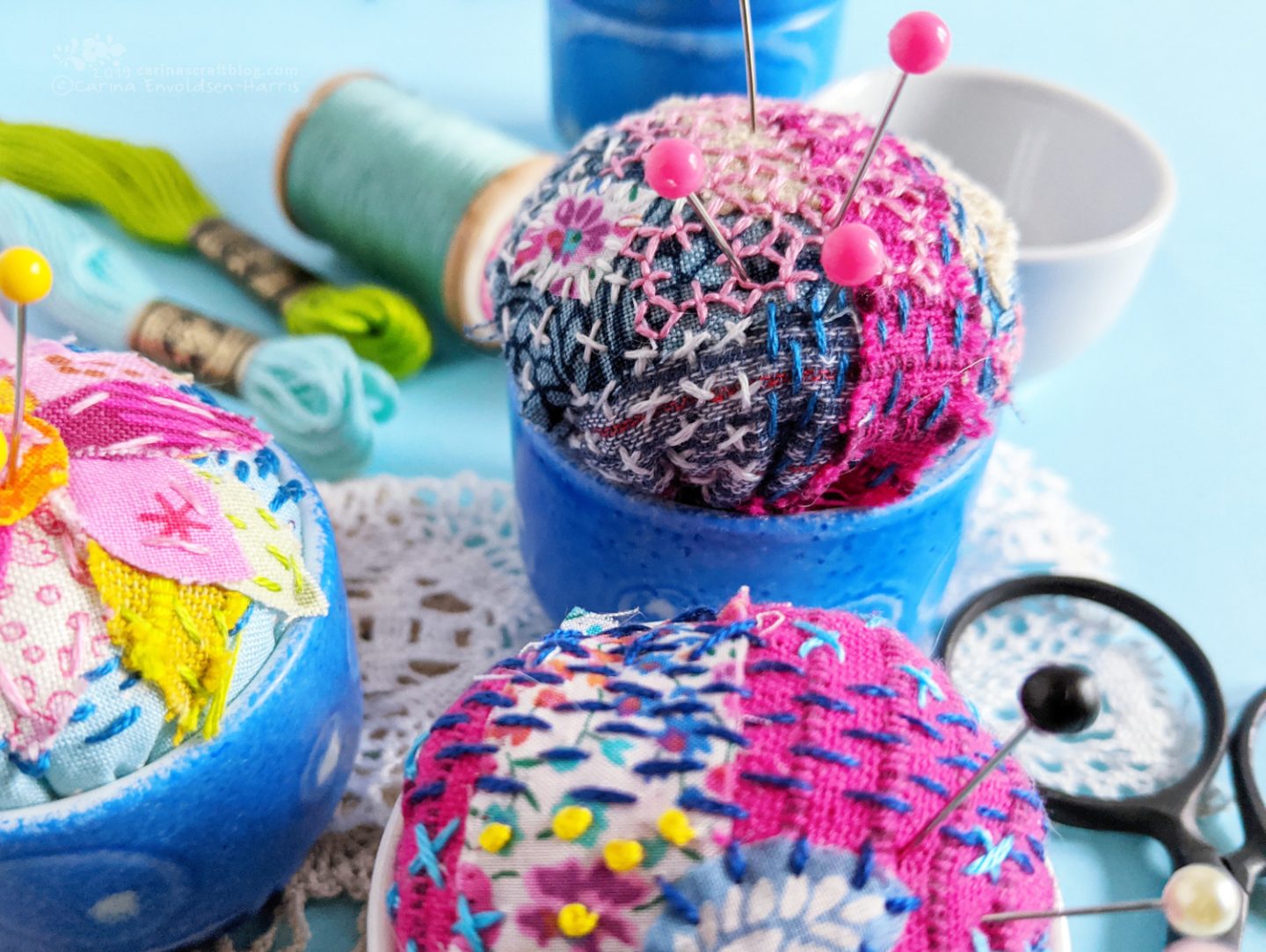 Egg cups turned into pincushions. Decorated with fabric scraps and stitching.