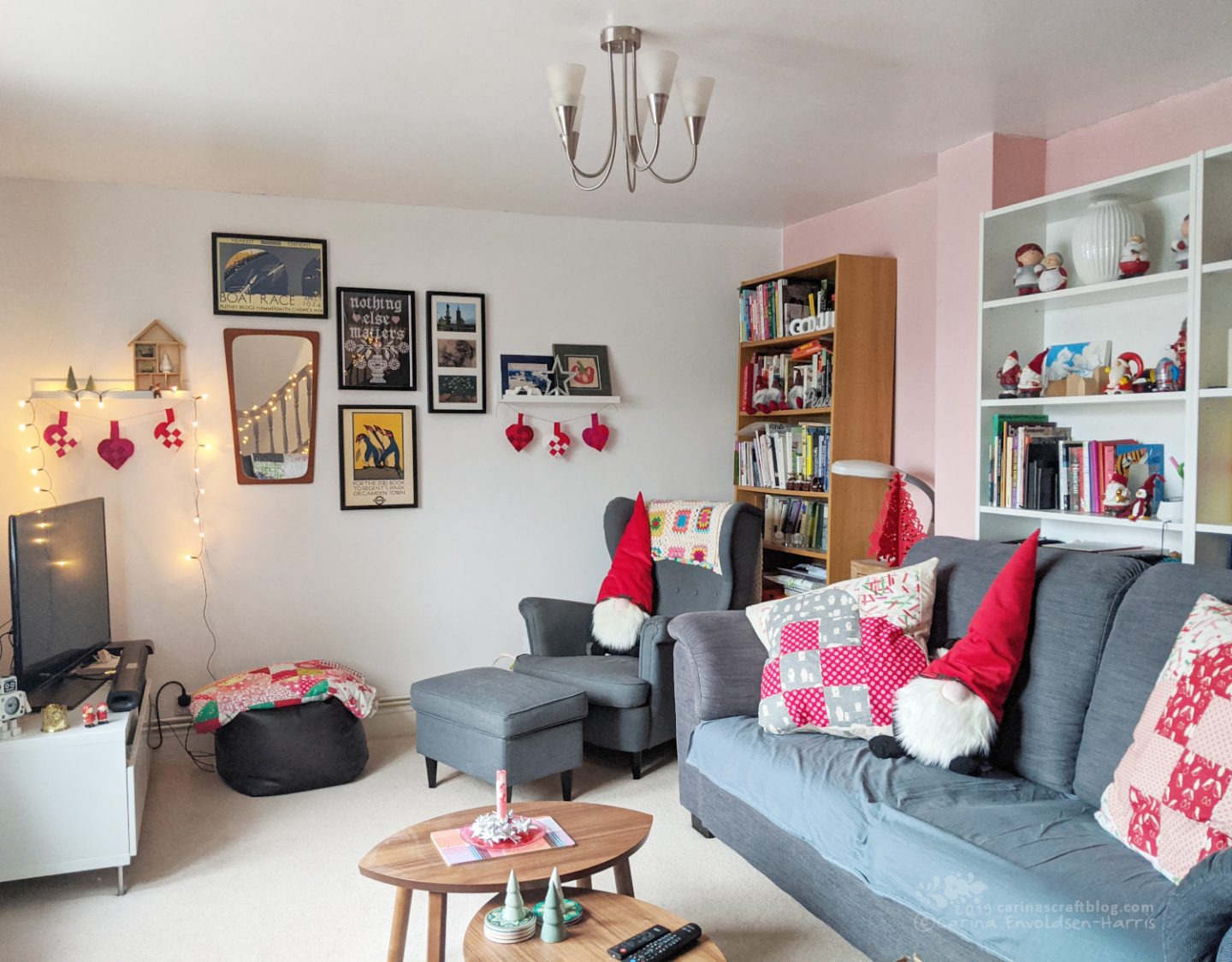 Living room with grey sofa and arm chair. Decorated with Christmasy cushions and other decorations, mainly in red and white.