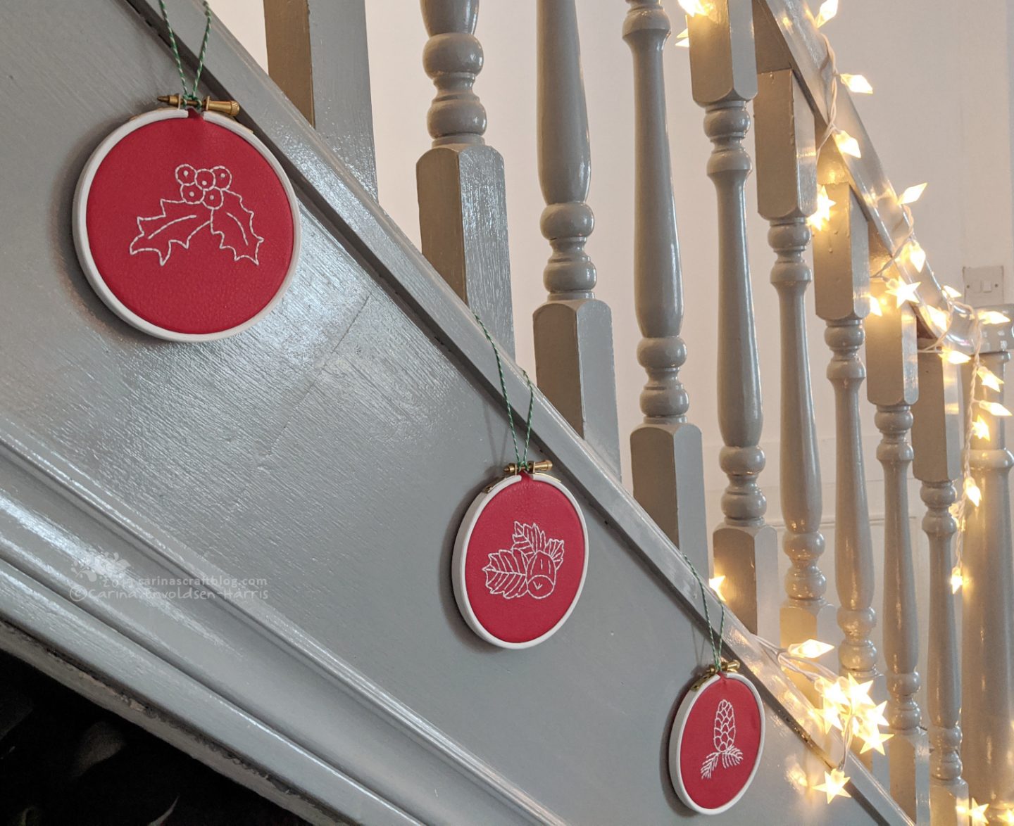 Grey staircase with embroideries in hoops hanging from the spindles.