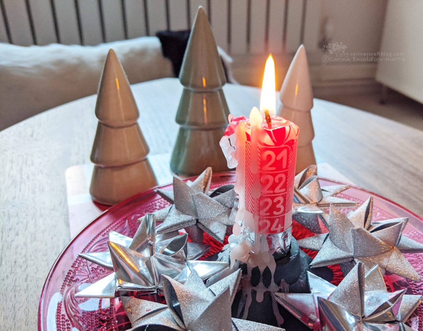 Almost burnt down advent candle surrounded by silver woven paper stars.