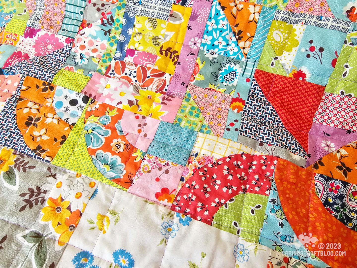 Close up of a quilt back. It is made up of pieces of fabrics in various shapes, sizes and colours.