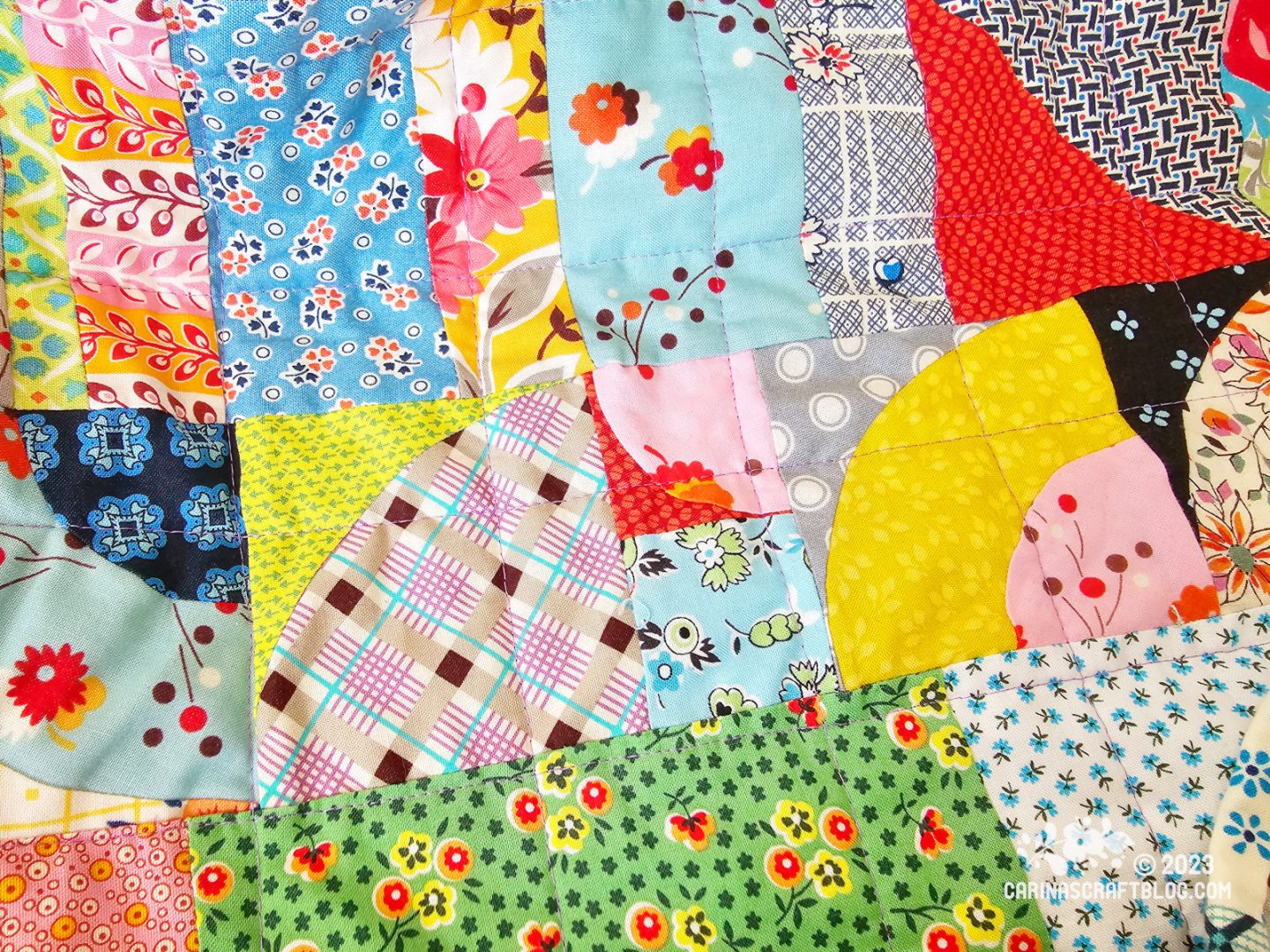 Close up of a quilt back. It is made up of pieces of fabrics in various shapes, sizes and colours.