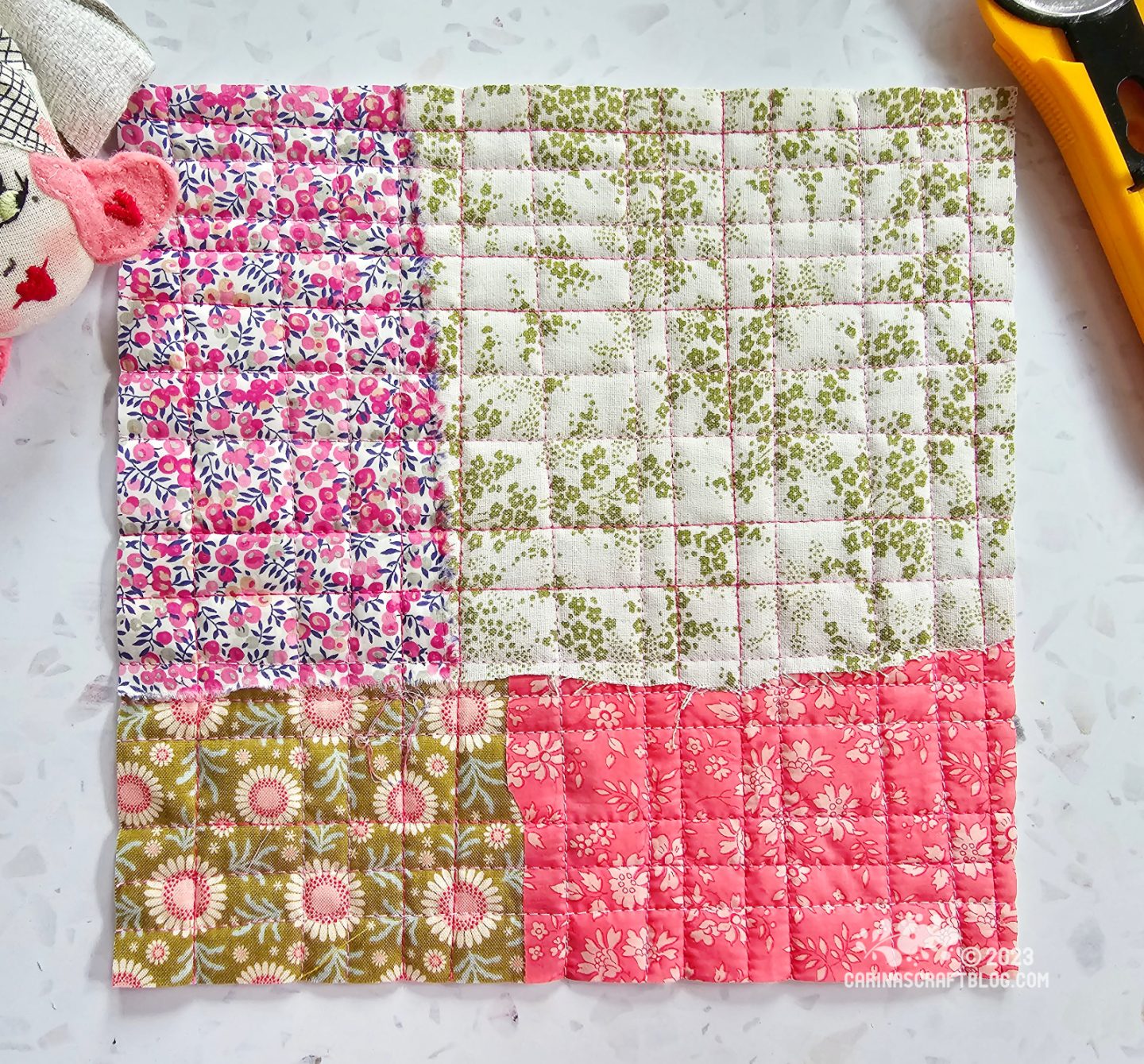 Small square quilt made up of four rectangles of different sizes in green and pink colours.