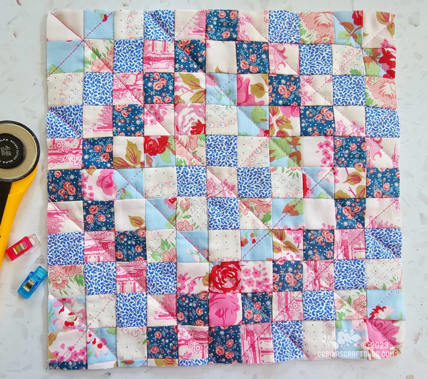 Small square quilt made of small squares pieced together to make a set of ever expanding boxes in pink and blue colours.