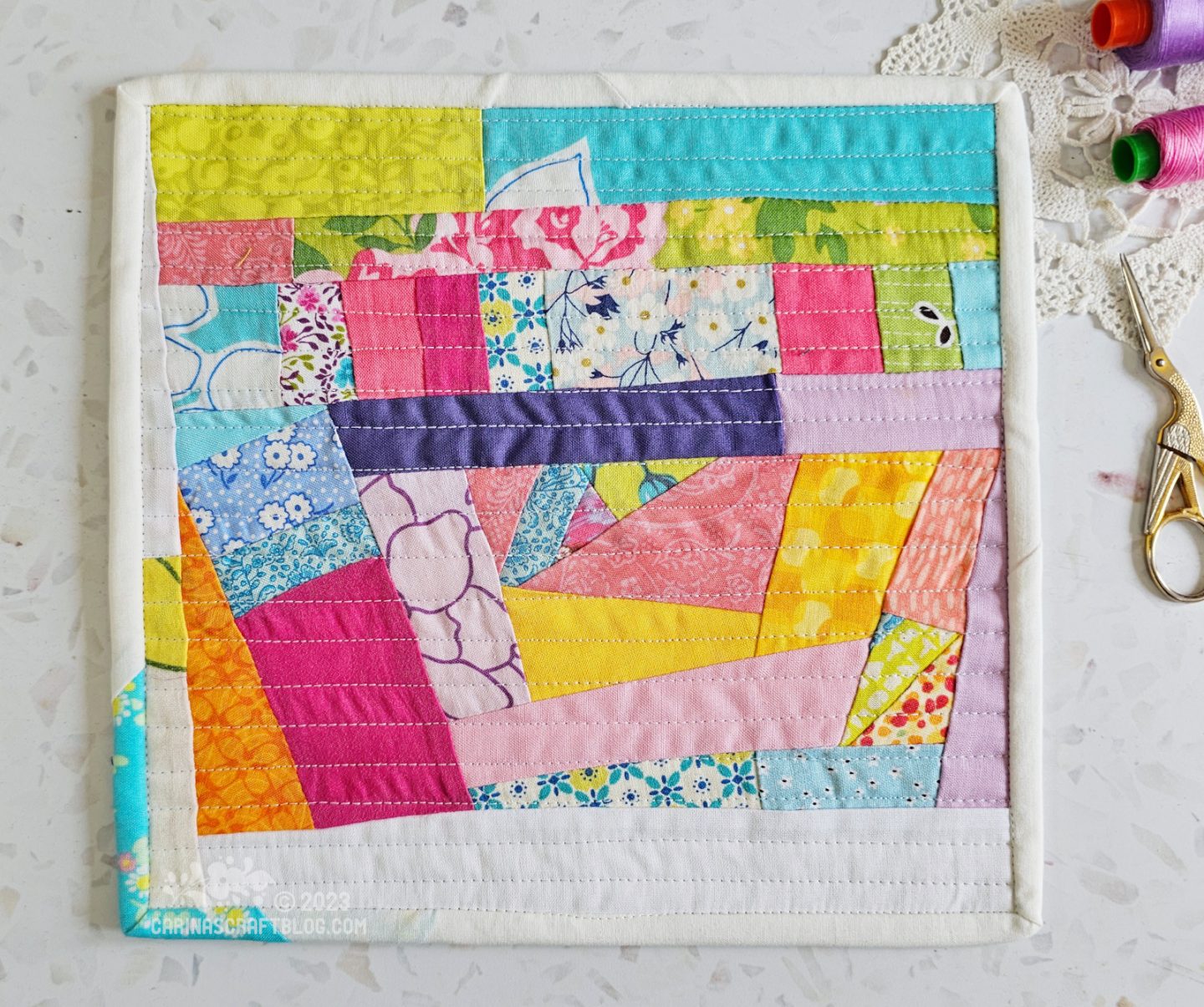 View from above of a mini quilt. Randomly pieced strips in a riot of colours.