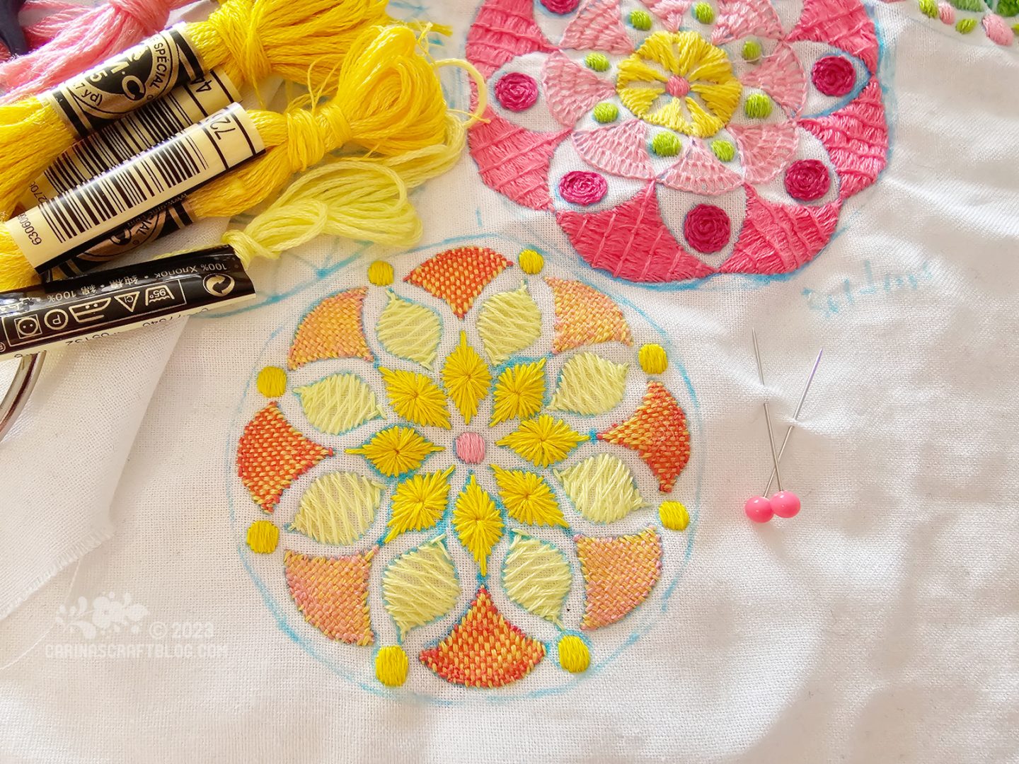 Close overhead view of a mandala inspired design in yellow and pink colours.