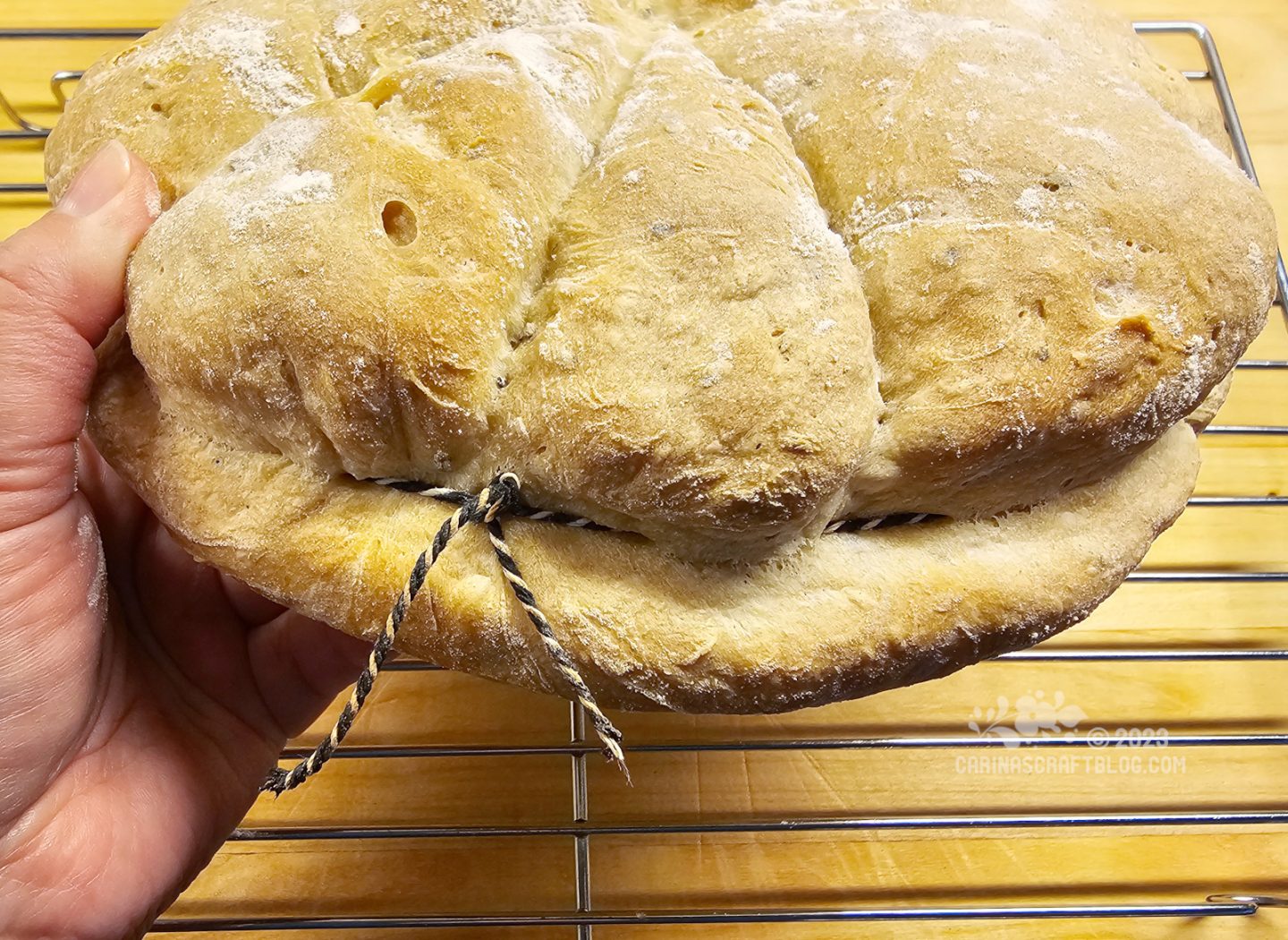 Side view of a round loaf of bread tied with a black and white string.