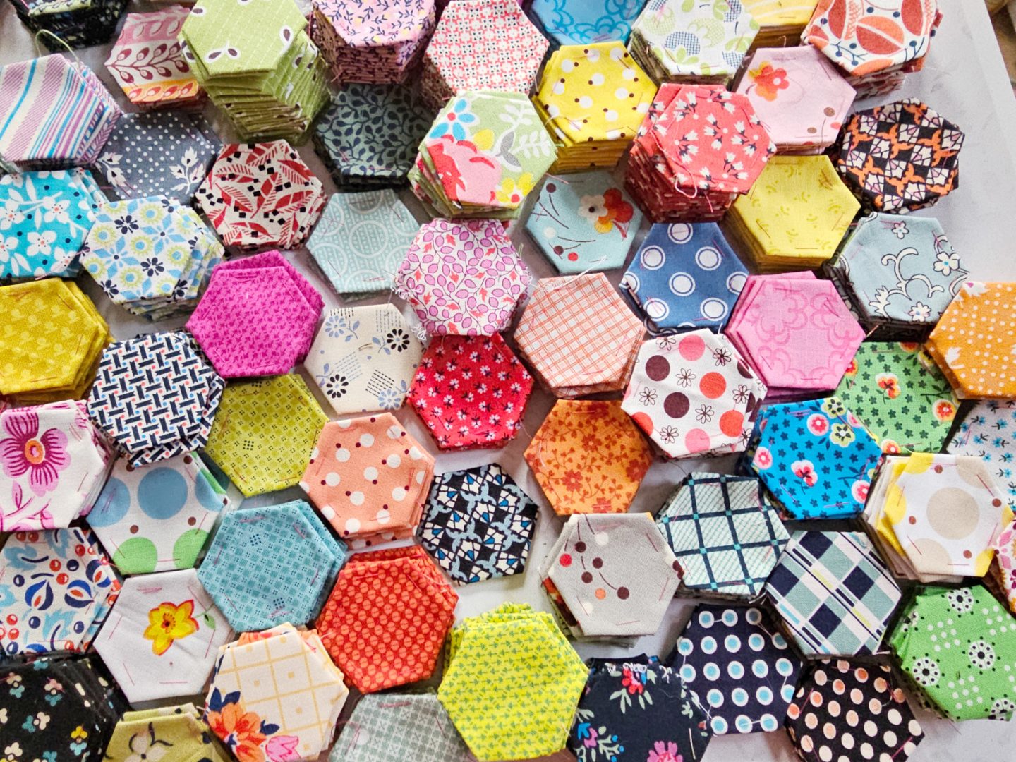 Overhead view of fabric hexagons in many different fabric prints.
