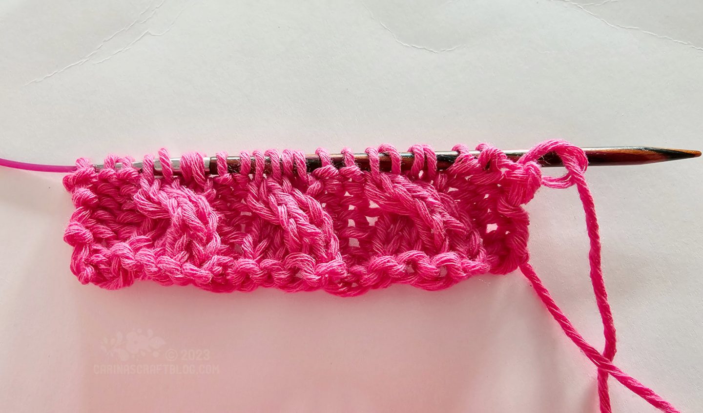 Overhead view of a short piece of knitting using hot pink year.