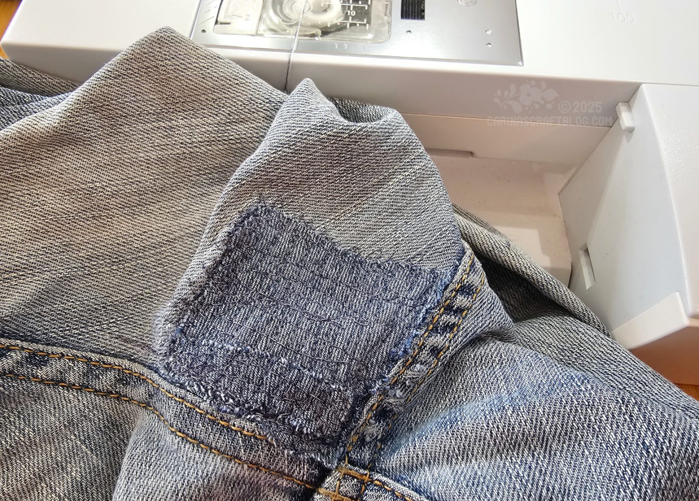 Photo of a pair of jeans. A section of the jeans has been mended with a patch in a similar fabric.