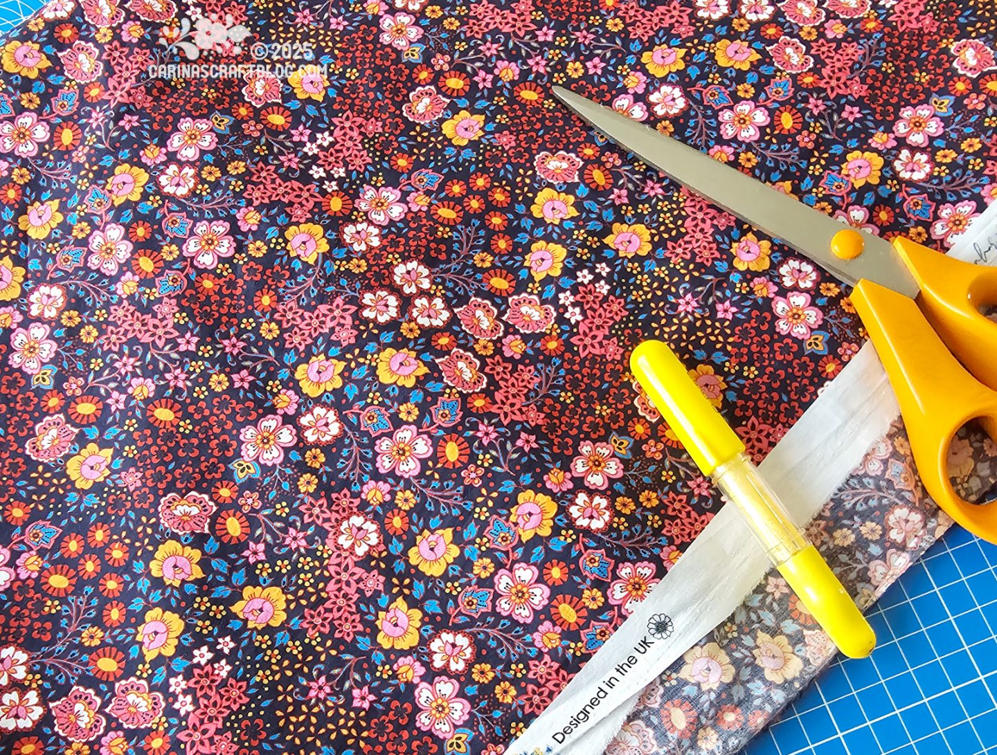 Photo of a large piece of fabric. The fabric is black with an all over print of small flowers in pink and yellow colours.